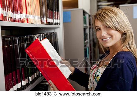 Stock Image - Hispanic woman searching for book in library. Fotosearch