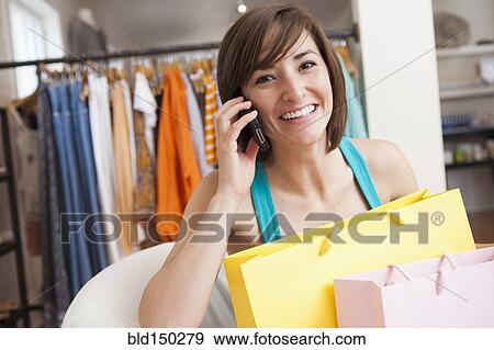 Stock Photo - Hispanic woman shopping in clothing store. Fotosearch