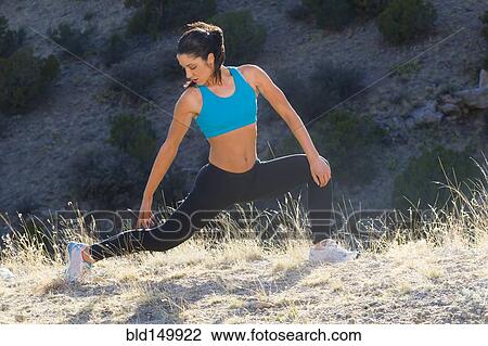 Stock Image - Hispanic woman stretching before exercise. Fotosearch