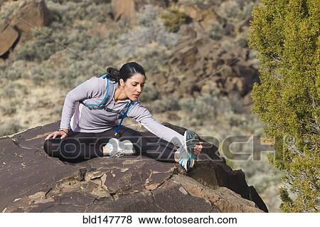 Stock Photo - Hispanic woman stretching on rock. Fotosearch
