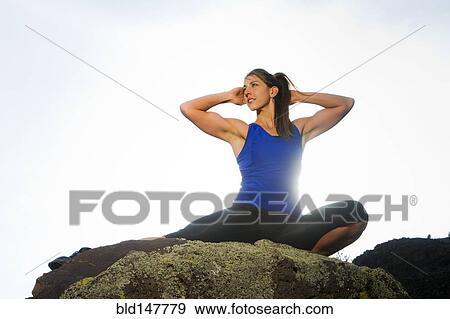 Stock Photo - Hispanic woman stretching on rock. Fotosearch