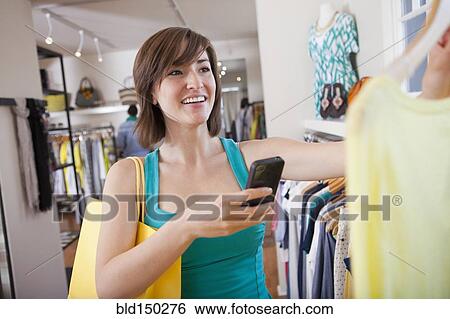Hispanic woman taking picture of shirt in clothing store View Large Photo Image Stock Photograph - Hispanic woman taking picture of shirt in clothing store. Fotosearch
