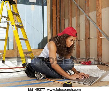 Stock Photo - Hispanic woman using laptop on construction site. Fotosearch