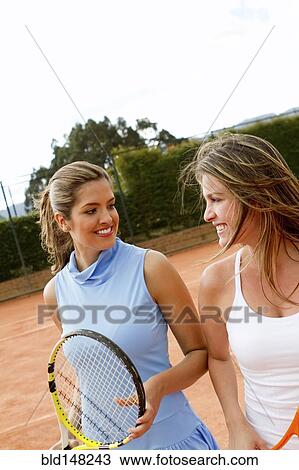 Stock Image - Hispanic women standing together on tennis court. Fotosearch