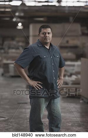 Stock Image - Hispanic worker standing in warehouse. Fotosearch