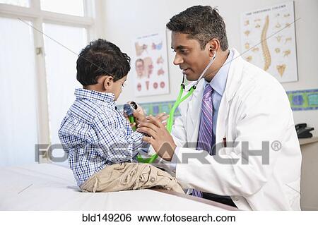 Stock Photograph - Indian doctor examining boy in doctor's office. Fotosearch