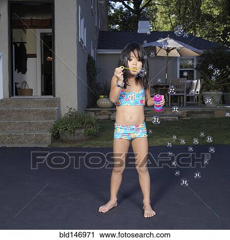 Stock Image - Korean girl in bikini blowing bubbles. Fotosearch