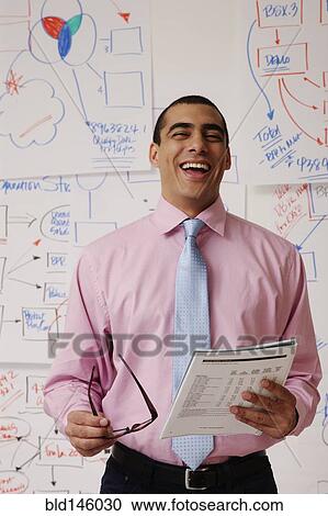 Laughing businessman standing with paperwork View Large Photo Image Stock Image - Laughing businessman standing with paperwork. Fotosearch