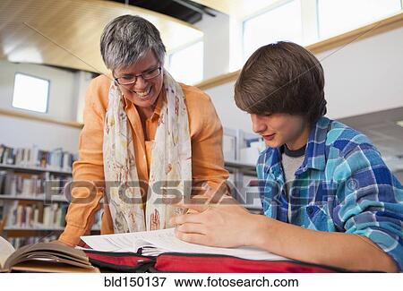 Librarian helping boy with homework in library View Large Photo Image Stock Photo - Librarian helping boy with homework in library. Fotosearch