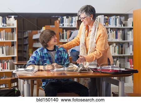 Librarian helping student in library View Large Photo Image Stock Image - Librarian helping student in library. Fotosearch