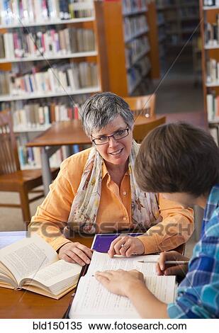 Stock Photography - Librarian helping student in library. Fotosearch