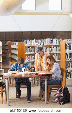 Stock Photo - Librarian helping students in library. Fotosearch