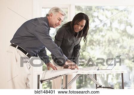Stock Image - Man and woman looking at blueprints together. Fotosearch