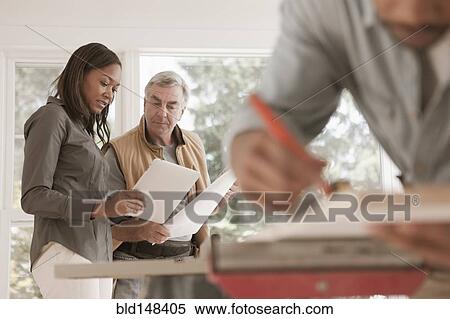 Stock Photography - Man and woman looking at blueprints together. Fotosearch