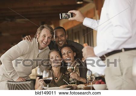Man taking photographs of friends in restaurant View Large Photo Image Stock Image - Man taking photographs of friends in restaurant. Fotosearch