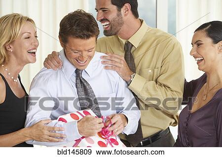 Man with friends opening birthday present View Large Photo Image Stock Photo - Man with friends opening birthday present. Fotosearch