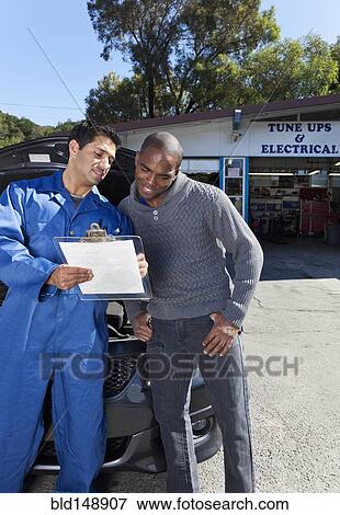 Stock Photo - Mechanic explaining paperwork to customer. Fotosearch