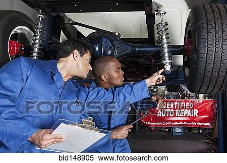 Stock Photography - Mechanics working on car shock absorbers. Fotosearch