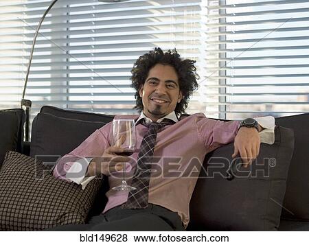 Middle Eastern man drinking red wine on sofa View Large Photo Image Stock Photo - Middle Eastern man drinking red wine on sofa. Fotosearch