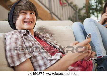 Mixed race boy using cell phone on sofa View Large Photo Image Picture - Mixed race boy using cell phone on sofa. Fotosearch
