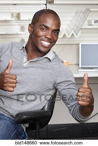 Stock Image - Mixed race businessman giving thumbs up in office. Fotosearch