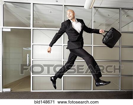 Mixed race businessman jumping in mid-air in office View Large Photo Image Stock Image - Mixed race businessman jumping in mid-air in office. Fotosearch