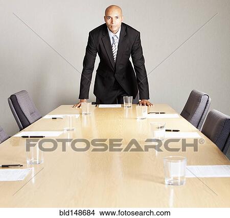 Mixed race businessman leaning on conference room table View Large Photo Image Picture - Mixed race businessman leaning on conference room table. Fotosearch