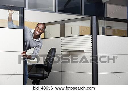 Stock Photograph - Mixed race businessman peering out from office cubicle. Fotosearch