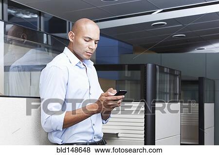 Stock Photo - Mixed race businessman text messaging on cell phone in office. Fotosearch