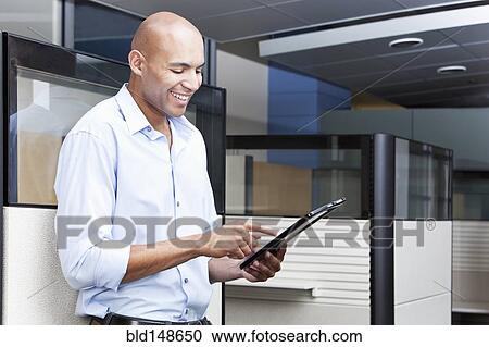 Stock Image - Mixed race businessman using digital tablet in office. Fotosearch