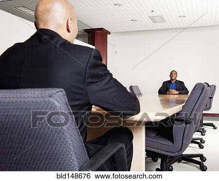 Stock Photograph - Mixed race businessmen having meeting in conference room. Fotosearch