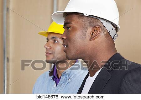 Stock Photography - Mixed race businessmen in hard hats. Fotosearch