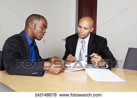 Mixed race businessmen reviewing contract in conference room View Large Photo Image Stock Photo - Mixed race businessmen reviewing contract in conference room. Fotosearch