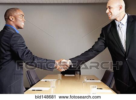 Mixed race businessmen shaking hands in conference room View Large Photo Image Stock Image - Mixed race businessmen shaking hands in conference room. Fotosearch