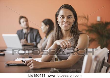 Stock Image - Mixed race businesswoman smiling at meeting table. Fotosearch