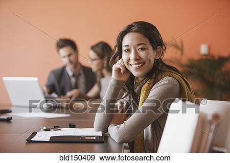 Mixed race businesswoman smiling at meeting table View Large Photo Image Stock Photo - Mixed race businesswoman smiling at meeting table. Fotosearch