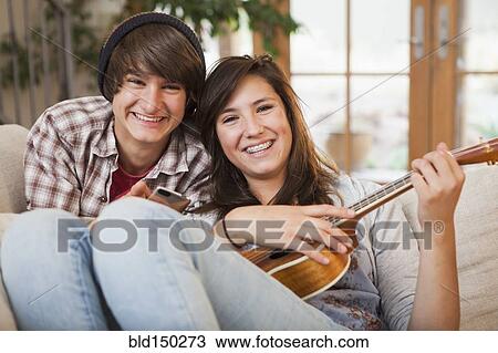 Stock Image - Mixed race couple sitting on sofa. Fotosearch