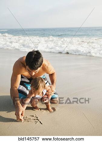 Stock Photo - Mixed race father and daughter writing in sand together. Fotosearch