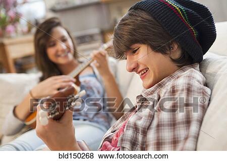 Mixed race friends playing ukuleles on sofa View Large Photo Image Stock Photo - Mixed race friends playing ukuleles on sofa. Fotosearch