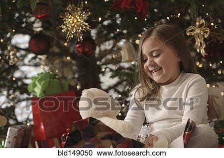 Stock Image - Mixed race girl opening gifts Christmas morning. Fotosearch