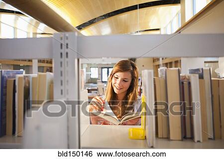 Stock Photograph - Mixed race girl reading book in library. Fotosearch