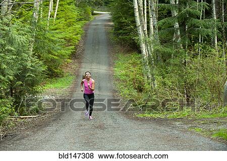 Stock Photo - Mixed race runner training on remote road. Fotosearch
