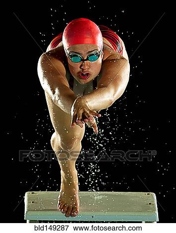 Stock Photo - Mixed race swimmer diving off starting block. Fotosearch