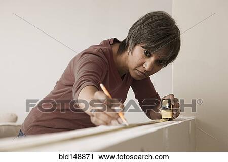Mixed race woman measuring wall in unfinished room View Large Photo Image Stock Image - Mixed race woman measuring wall in unfinished room. Fotosearch