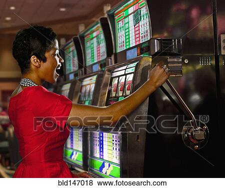 Stock Photo - Mixed race woman playing slot machines in casino. Fotosearch