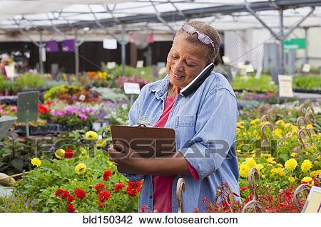 Mixed race woman talking on telephone in plant nursery View Large Photo Image Stock Image - Mixed race woman talking on telephone in plant nursery. Fotosearch