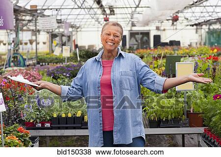 Mixed race woman working in plant nursery View Large Photo Image Stock Photo - Mixed race woman working in plant nursery. Fotosearch