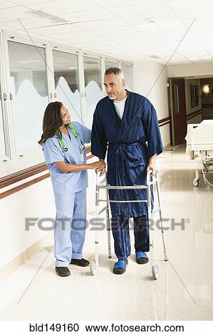 Nurse helping patient use walker in hospital View Large Photo Image Stock Image - Nurse helping patient use walker in hospital. Fotosearch