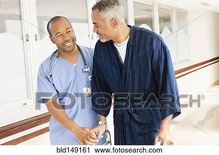 Stock Image - Nurse helping patient use walker in hospital. Fotosearch