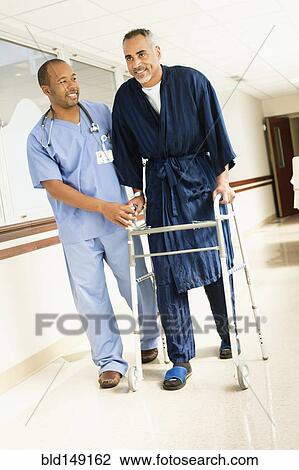 Stock Image - Nurse helping patient use walker in hospital. Fotosearch